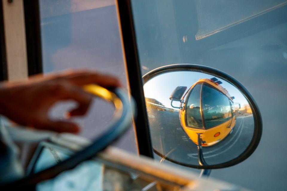 Bus driver trainee Anthony Thomas holds the steering wheel as the bus is reflected in the convex mirror at the Coachella Valley Unified School District in Thermal, Calif., on August 31, 2022. 