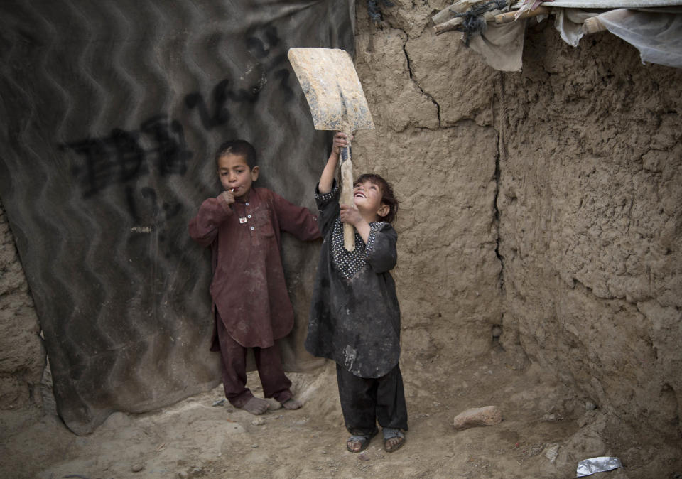 FILE - A young Afghan girl plays with a broken shovel outside her makeshift house at a refugee camp in Kabul, Afghanistan, Friday, May 10, 2013. Thousands of Afghans displaced by the war in their own country live in slum-like conditions in refugee camps on the edge of the capital. (AP Photo/Anja Niedringhaus, File)