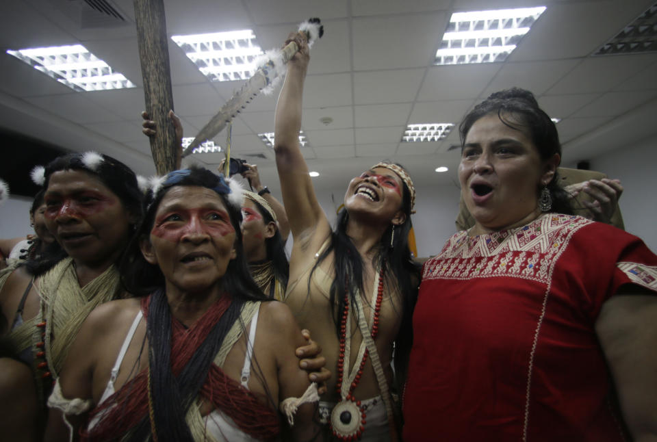 Waoranis leader Nemonte Nenquimo, center, and lawyer Lina Espinosa, right, celebrate after a judged ruled in their favor in a lawsuit filed against the Ministry of Non-Renewable Natural Resources for opening up oil concessions on their ancestral land, in Puyo, Ecuador, Friday, April 26, 2019. (AP Photo/Dolores Ochoa)