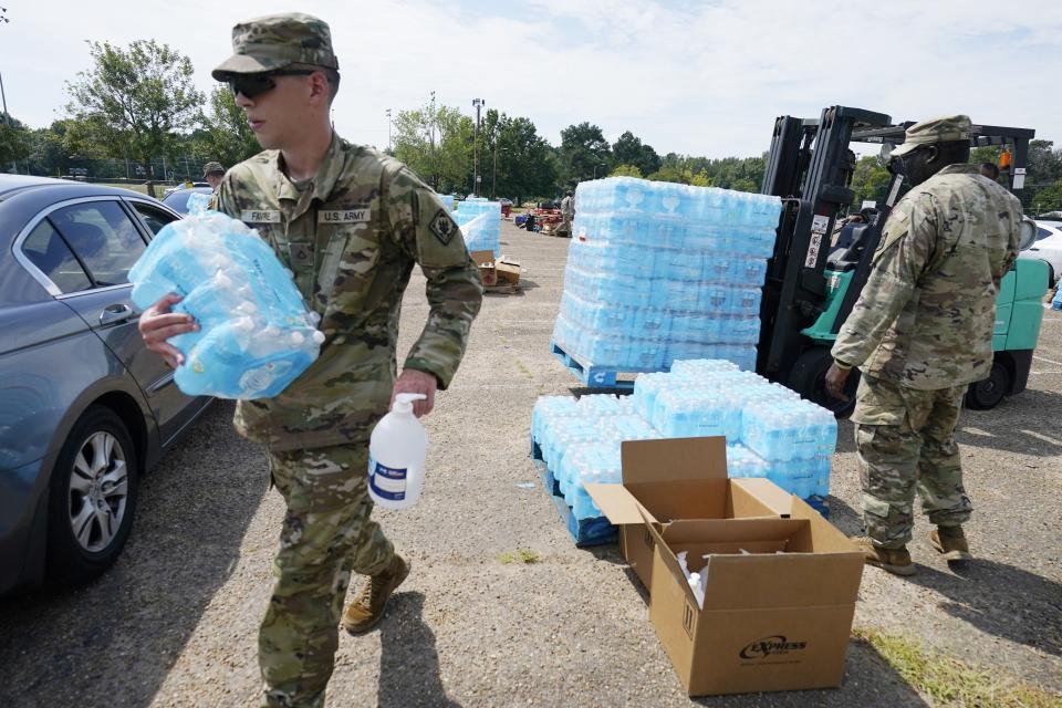 Mississippi National Guardsmen carry cases of drinking water and a bottle of hand sanitizer to Jackson, Miss., residents on Sept. 2. Jackson's water system partially failed following flooding and heavy rainfall that exacerbated longstanding problems in one of two water-treatment plants.