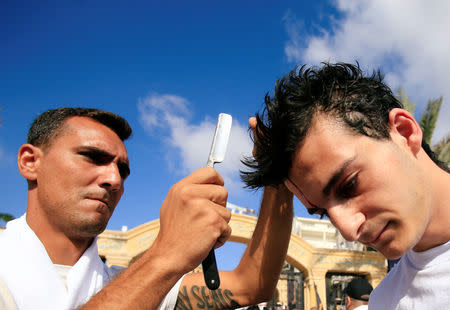 A Lebanese Shi'ite Muslim taps the head of a man with a razor to draw blood during a religious procession to mark Ashura in Nabatiyeh town, southern Lebanon September 20, 2018. REUTERS/ Ali Hashisho