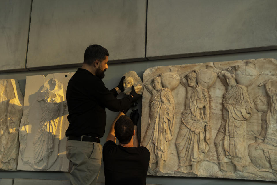 Acropolis Museum staff place a male head on the frieze of the Acropolis museum during a ceremony for the repatriation of three sculpture fragments, in Athens, on Friday, March 24, 2023. Greece received three fragments from the ancient Parthenon temple that had been kept at Vatican museums for two centuries. Culture Ministry officials said the act provided a boost for its campaign for the return of the Parthenon Marbles from the British Museum in London. (AP Photo/Petros Giannakouris)