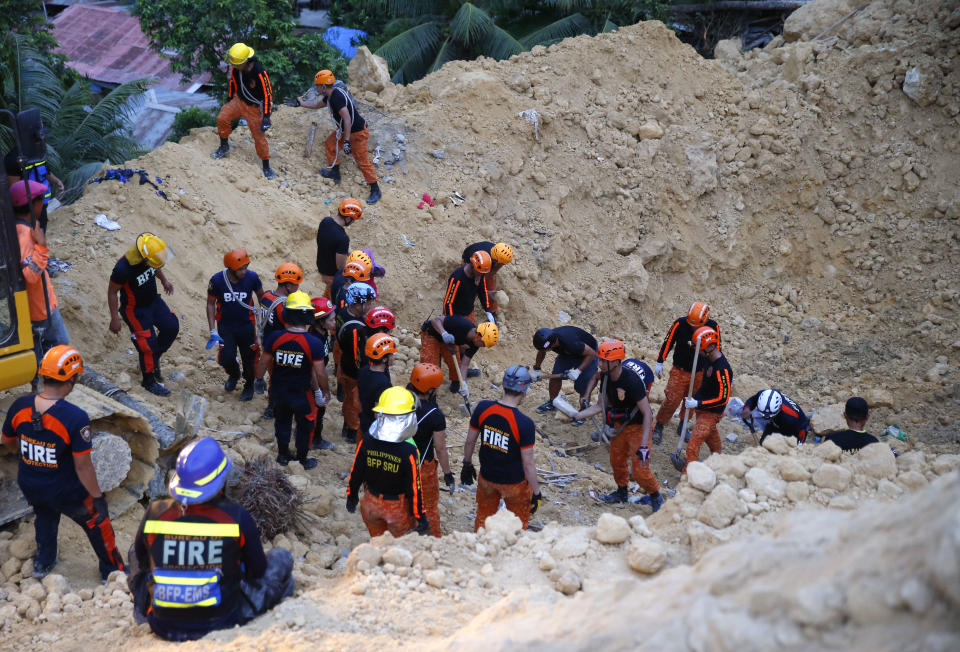 Rescuers dig through the rubble to search for possible survivors following a landslide that buried dozens of homes in Naga city, Cebu province central Philippines on Thursday Sept. 20, 2018. A landslide set off by heavy rains buried homes under part of a mountainside in the central Philippines on Thursday, and several people are feared buried, including two who sent text messages seeking help. (AP Photo/Bullit Marquez)