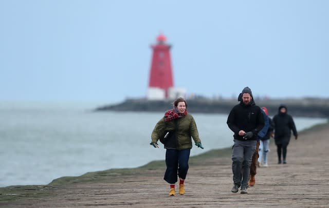 People walk on the Great South wall in Dublin as the wind picks up