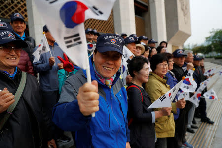 Supporters hold South Korean flags while waiting for a convoy transporting South Korean President Moon Jae-in to leave the Presidential Blue House for the inter-Korean summit, in Seoul, South Korea, April 27, 2018.