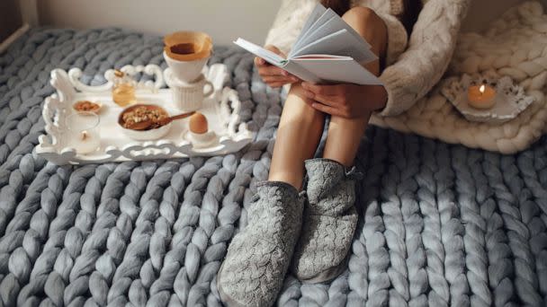 PHOTO: Woman with long hair drinking hot coffee and reading book in bed. (STOCK IMAGE/Getty Images)