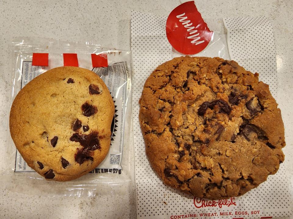 A small chocolate-chip cookie from KFC next to a larger, darker cookie from Chick-fil-A