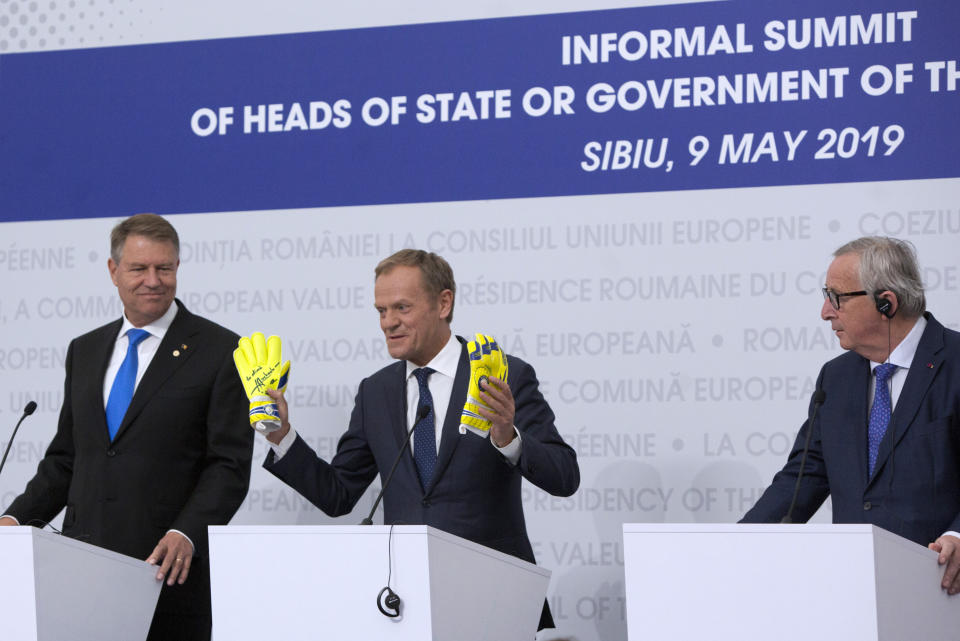 European Council President Donald Tusk, center, holds up a pair of mitts he received from retired Romanian soccer goalkeeper Helmuth Duckadam during a media conference at an EU summit in Sibiu, Romania, Thursday, May 9, 2019. The European Union will be holding an extra summit two days after the May 26 European elections to assess who should get three top jobs that will be vacated in the fall. (AP Photo/Virginia Mayo)