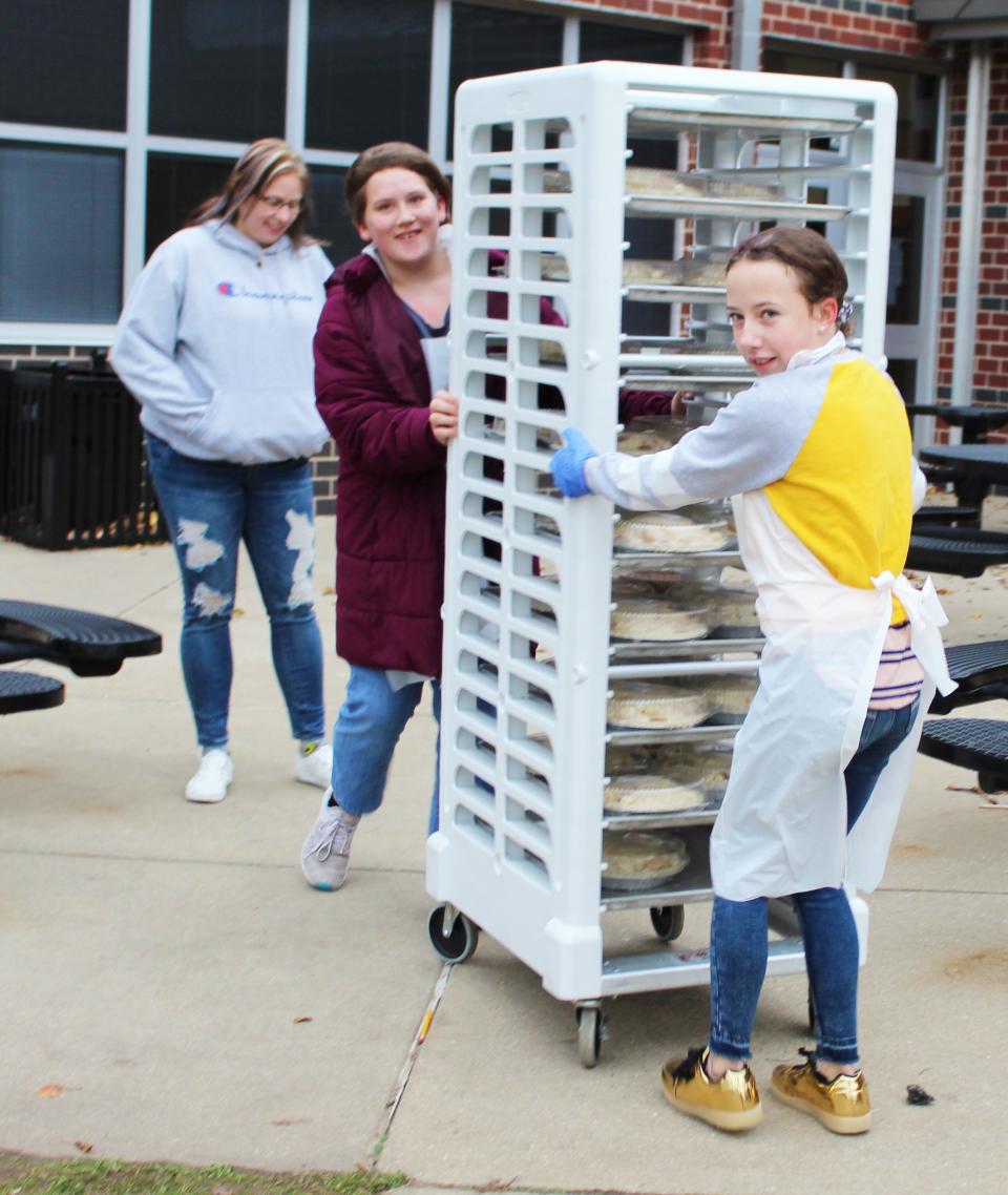 Betty Tullos and Hermynee Kirsch take a load of finished apple pies to a customer's car.