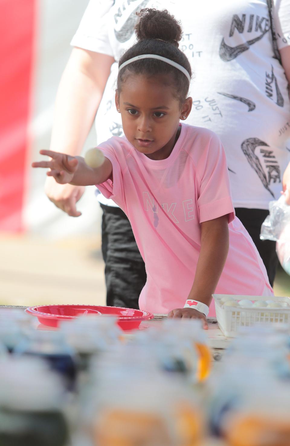 Five-year-old Ryelyn Ude-Umanta tries to win a goldfish by putting a ping pong ball in a bowl at the 2021 Stark County Fair.