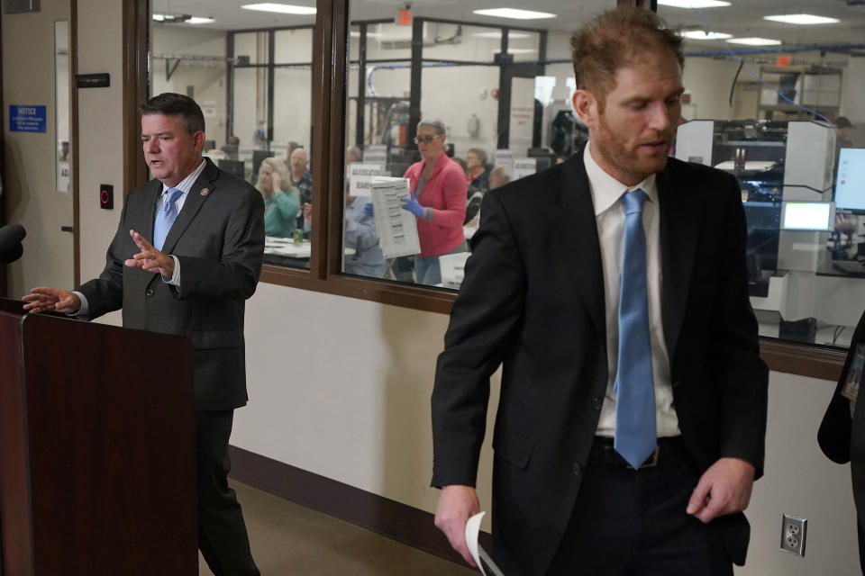 Election workers tabulate ballots in the background as Maricopa County Supervisor Bill Gates speaks and Maricopa County Recorder Stephen Richer steps aside, right, inside the Recorders Office, Wednesday, Nov. 9, 2022, in Phoenix. (AP Photo/Matt York)