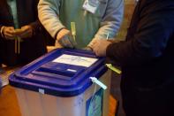 An Iranian man closes an empty ballot box before starting the vote at a polling station during parliamentary elections in Tehran