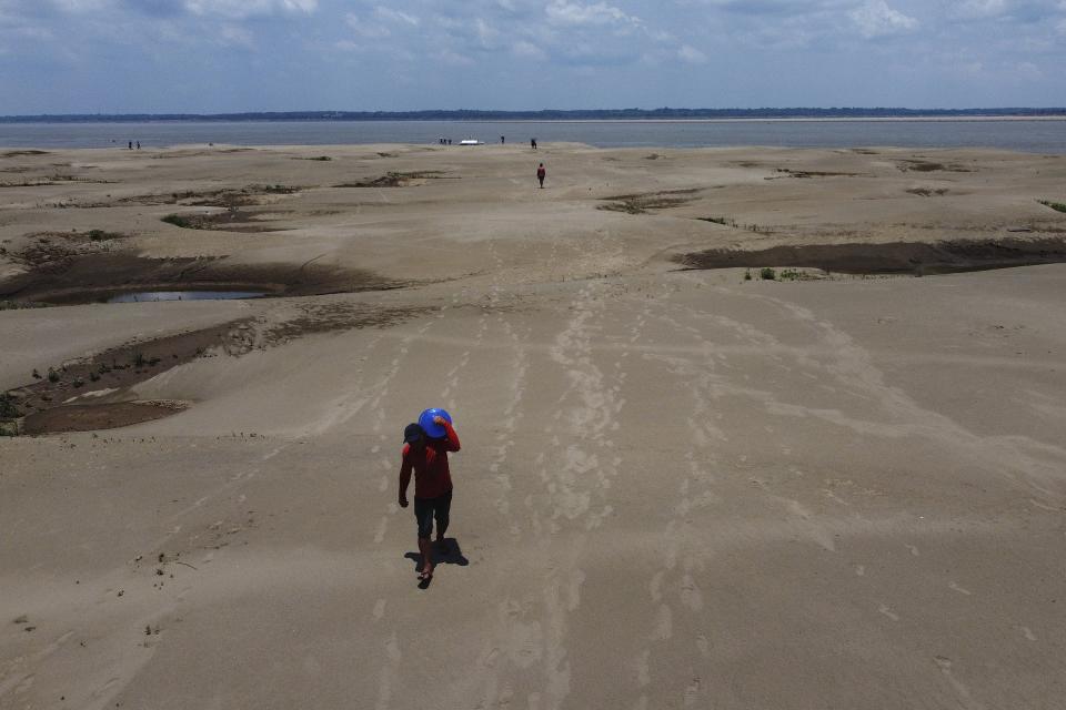 FILE - Residents of a riverside community carry food and containers of drinking water from an aid distribution due to the ongoing drought in Careiro da Varzea, Amazonas state, Brazil, Oct. 24, 2023. Earth last year shattered global annual heat records, the European climate agency said Tuesday, Jan. 9, 2024. (AP Photo /Edmar Barros, File)