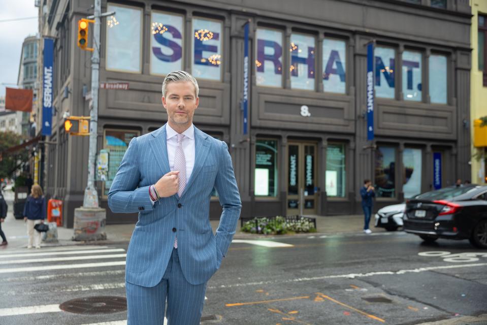 Ryan Serhant poses in front of the modern gray SoHo offices of his namesake brokerage.