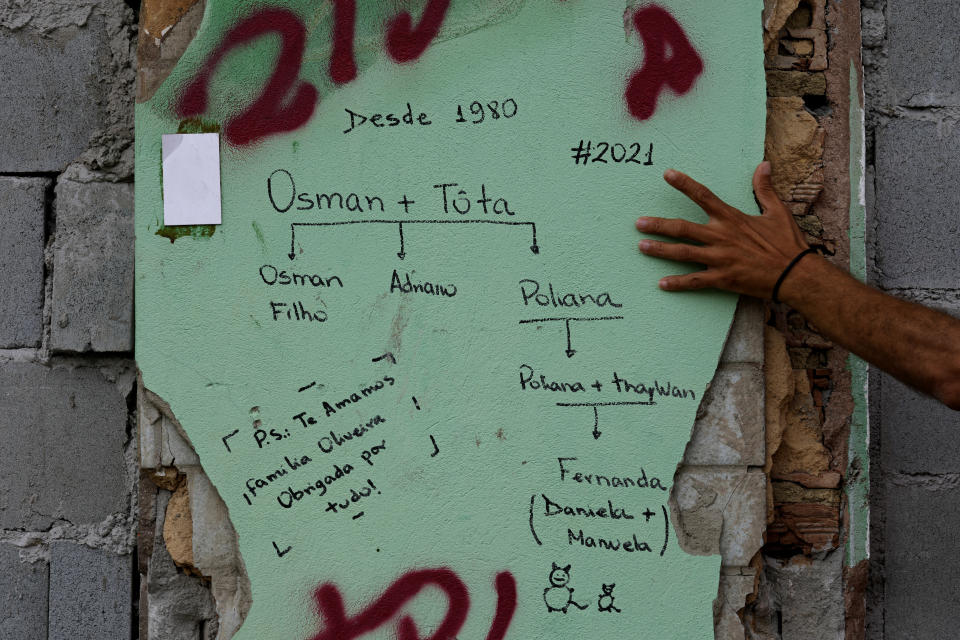 Paulo Sergio Doe shows a family tree sketched on a damaged wall of a neighbor's home in the Pinheiro neighborhood of Maceio, Alagoas state, Brazil, Sunday, March 6, 2022. The family has vacated their home, one of many that have been damaged by ground subsidence caused by the Braskem mine. (AP Photo/Eraldo Peres)