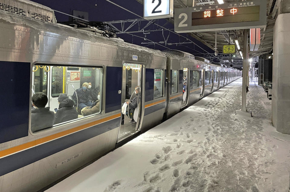 A train stops due to a power outage at Nishioji Station in Kyoto, western Japan Wednesday, Jan. 25, 2023. Snow and cold weather were affecting much of Japan on Wednesday, disrupting highway, air and train travel, and more snow and cold temperatures were forecast. (Kyodo News via AP)