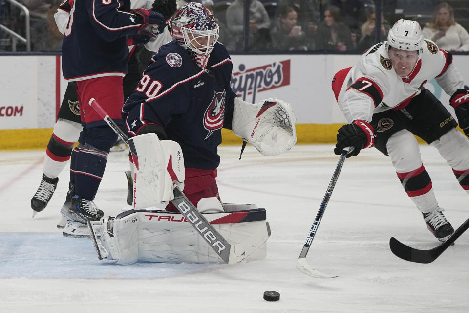 Ottawa Senators left wing Brady Tkachuk (7) reaches for the puck in front of Columbus Blue Jackets goaltender Elvis Merzlikins (90) during the first period of an NHL hockey game Friday, Dec. 1, 2023, in Columbus, Ohio. (AP Photo/Sue Ogrocki)