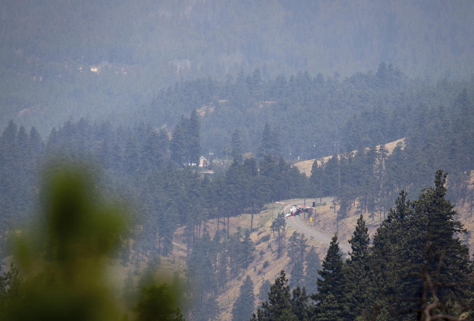 A helicopter pilot descends to pick up water while battling a wildfire burning in Lytton, British Columbia, Friday, July 2, 2021. Officials on Friday hunted for any missing residents of a British Columbia town destroyed by wildfire as Canadian Prime Minister Justin Trudeau offered federal assistance. (Darryl Dyck/The Canadian Press via AP)