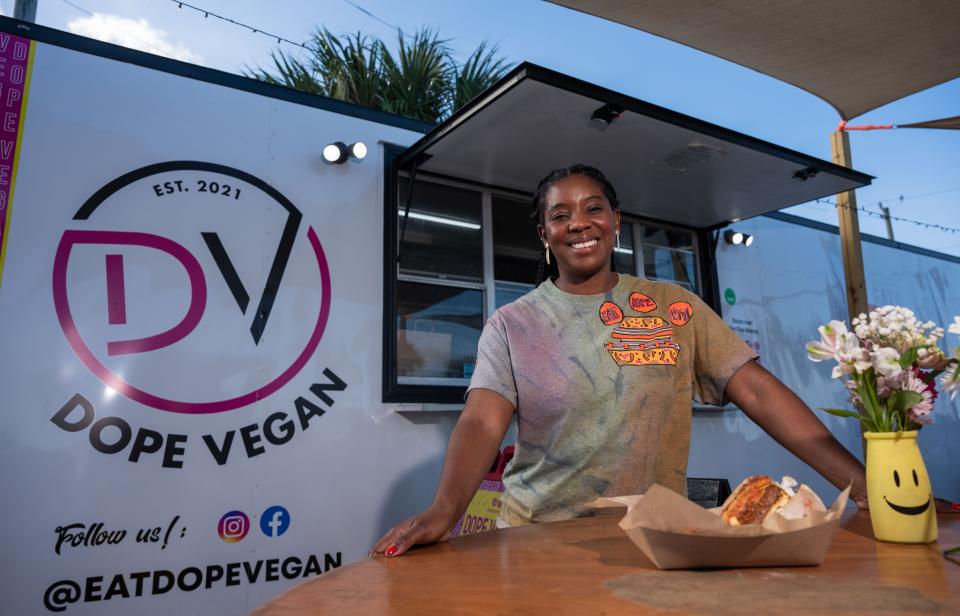 Rhona Nain, owner/CEO of Dope Vegan, stands in front of her food truck, showcasing her signature Dope Burger. Nain combines comfort food, seasonings and sauces from her native Jamaica and a love for plant-based foods.