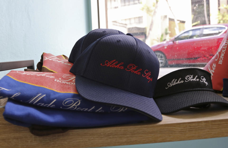 This Tuesday, April 16, 2019, photo shows merchandise at Aloha Poke Shop, a store in Honolulu that received a letter from Chicago-based Aloha Poke Co. saying the Illinois company had trademarked "Aloha Poke" and the Hawaii company would need to change its name. Hawaii lawmakers are considering adopting a resolution calling for the creation of legal protections for Native Hawaiian cultural intellectual property. (AP Photo/Audrey McAvoy)