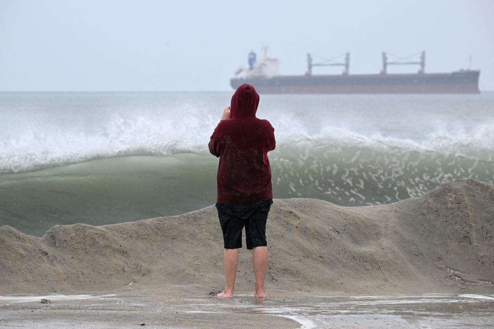 A beachgoer watches the waves crash along the shore in Long Beach, Calif.