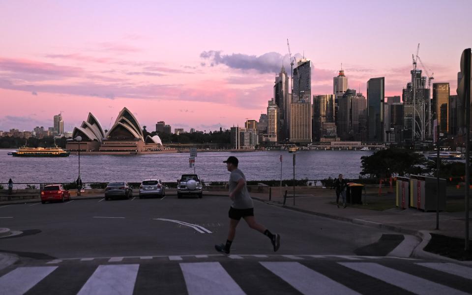 he Sydney Opera House can be seen as a man crosses the road at Milson's Point, during lockdown in Sydney, Australia, Wednesday, July 7, 2021. The coronavirus lockdown in Greater Sydney and surrounds will be extended by a week after NSW recorded 27 new local COVID-19 cases. - Getty Images