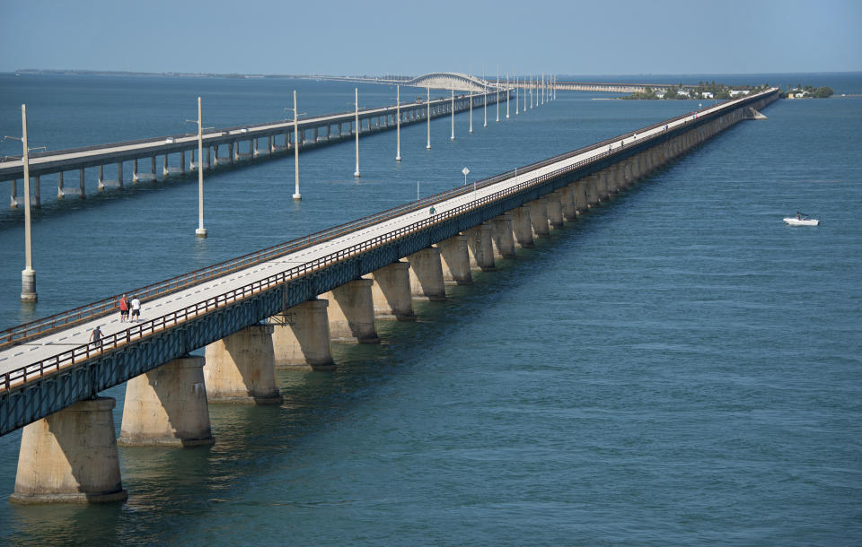 This aerial photo provided by the Florida Keys News Bureau shows the historic Seven Mile Bridge, right, in the Florida Keys near Marathon, Fla., Wednesday, March 19, 2014. The Monroe County Commission Wednesday, March 19, 2014, ratified an agreement between the Florida Department of Transportation, the City of Marathon and the county to begin a 30-year, $77 million restoration and maintenance program on a 2.2-mile segment of the century-old span between Marathon and Pigeon Key. The bridge that once supported Henry Flagler's Florida Keys OverSea Railroad was retired in 1982, after the new span, left, opened to traffic. (AP Photo/Florida Keys News Bureau, Andy Newman)