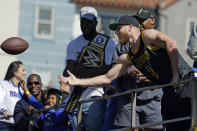 Los Angeles Rams wide receiver Cooper Kupp, right, tosses a football to a fan as he rides on a bus during the team's victory parade in Los Angeles, Wednesday, Feb. 16, 2022, following their win Sunday over the Cincinnati Bengals in the NFL Super Bowl 56 football game. (AP Photo/Marcio Jose Sanchez)