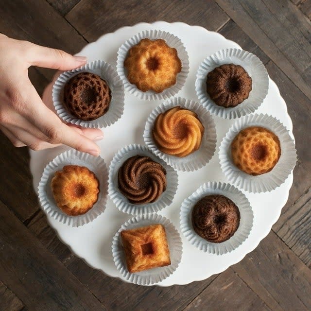 Hand picks a pastry from a plate of assorted mini bundt cakes