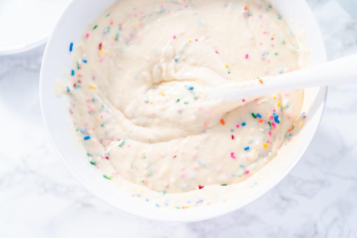 Mixing ingredients to bake birthday funfetti cake with colorful sprinkles.