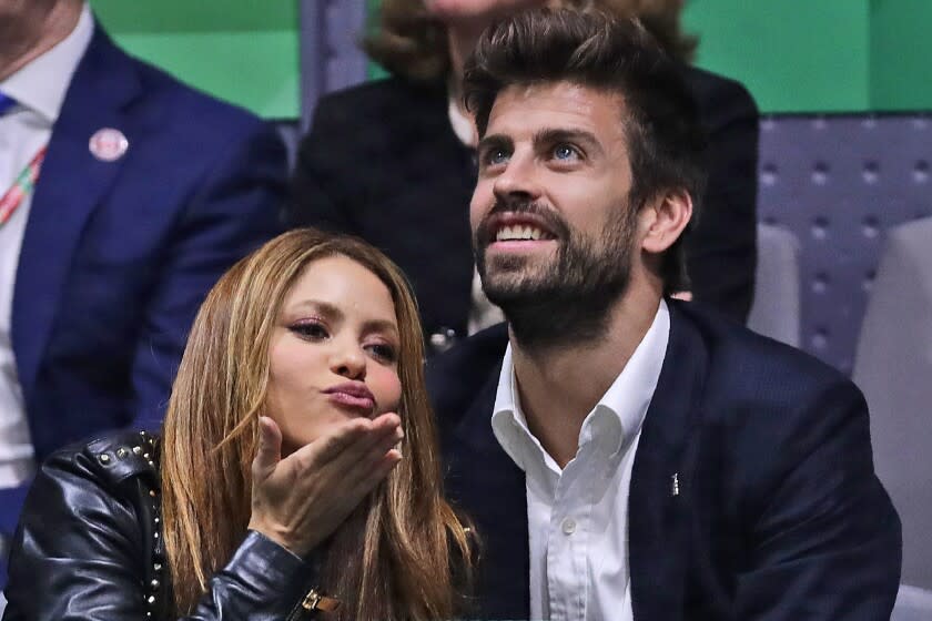 A woman blowing a kiss next to a man wearing a suit