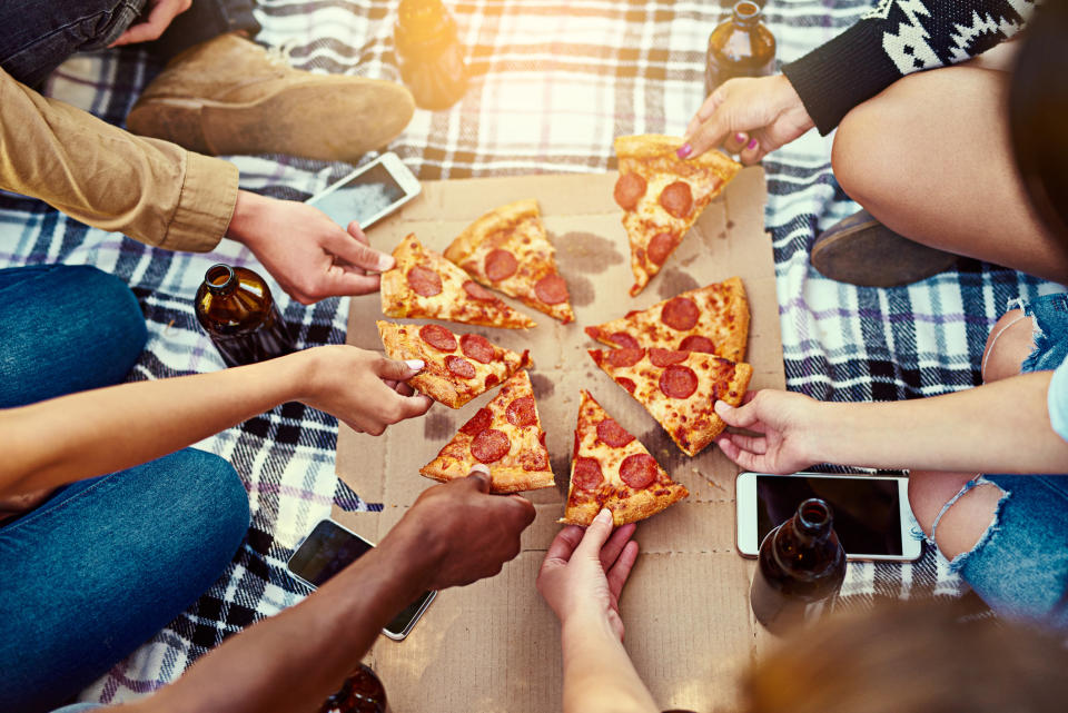 Cropped shot of a group of friends eating pizza while having a picnic