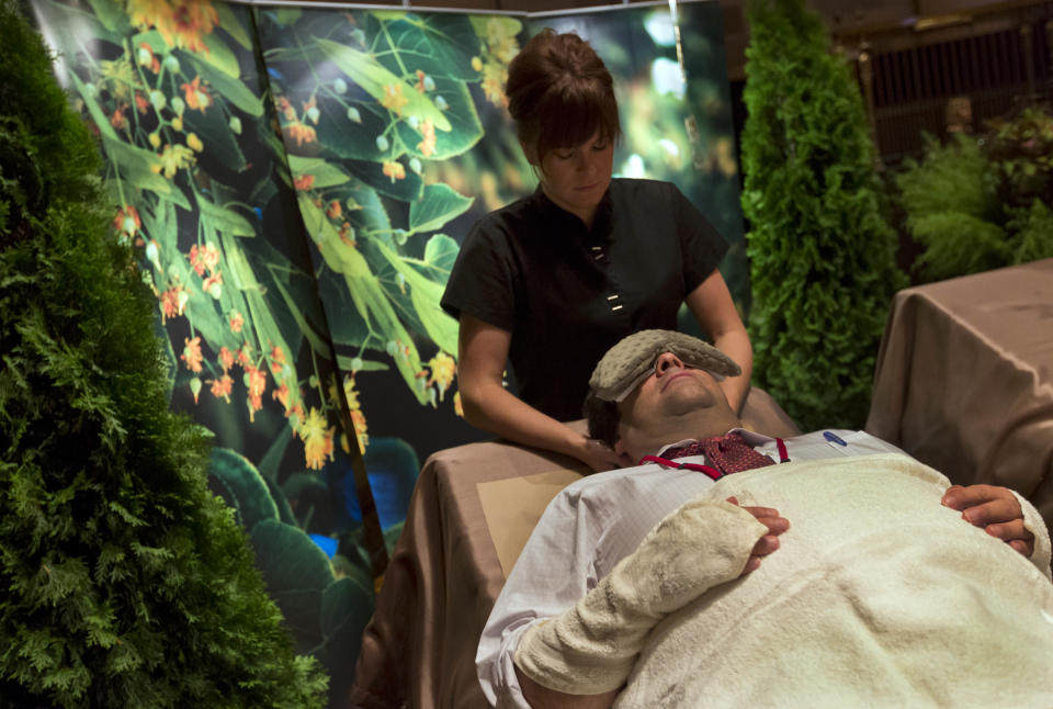 This Aug. 15, 2013 photo shows a man receiving a Trilogy of Linden treatment from Brooke Hess, with the Aspira Spa at the Osthoff Resort, in Elkhart Lake, Wis., during the International Spa Association event in New York. The 150-minute treatment uses honey and blossoms from the indigenous trees for facials, a body mask and a massage. (AP Photo/Richard Drew)