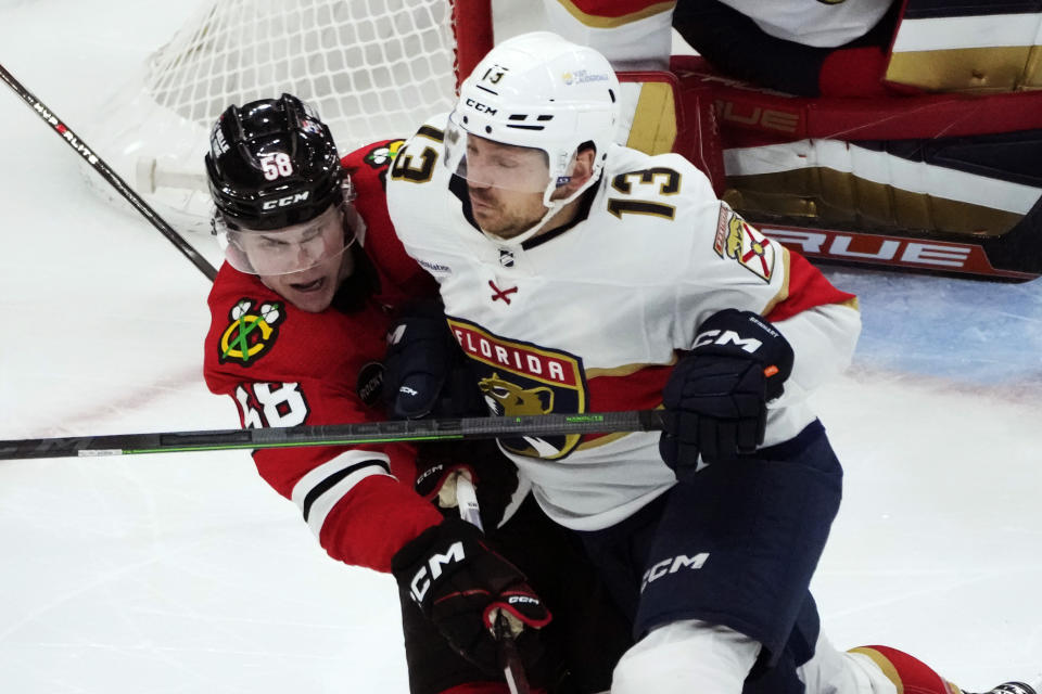 Florida Panthers' Sam Reinhart (13) checks Chicago Blackhawks' MacKenzie Entwistle during the third period of an NHL hockey game Saturday, Nov. 4, 2023, in Chicago. (AP Photo/Charles Rex Arbogast)