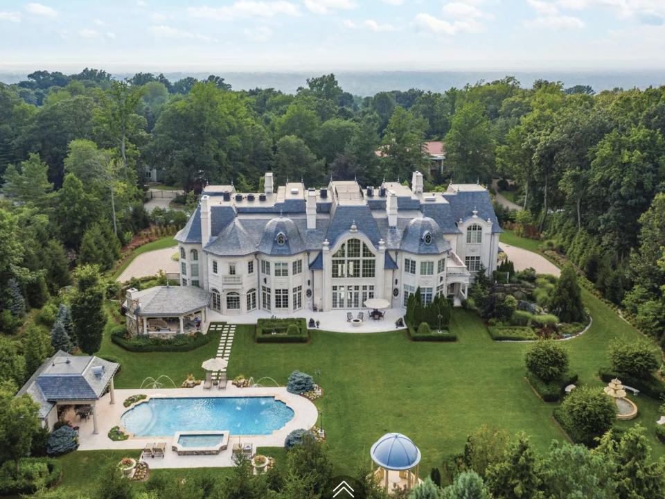 a sprawling mansion with swimming pool and lawn surrounded by trees in New Jersey