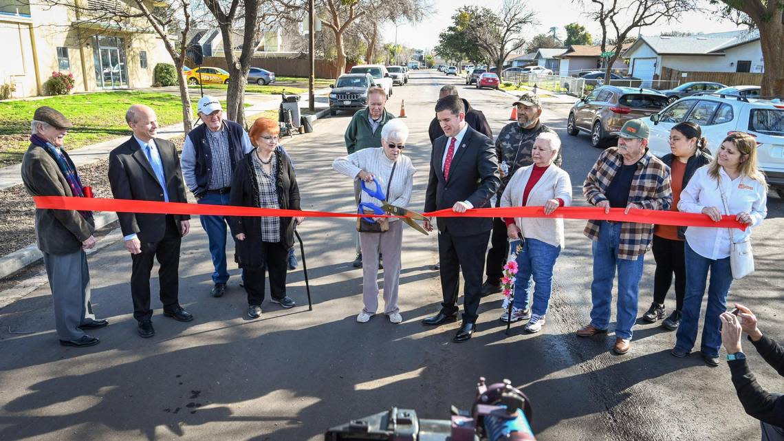 Fresno City Council President Tyler Maxwell, center right, stands with central Fresno resident Donna Krum as she cuts a ribbon alongside neighbors and city officials to celebrate the repaving and reconstruction of streets that had not been repaved in over 50 years, on Tuesday, Feb. 7, 2023.