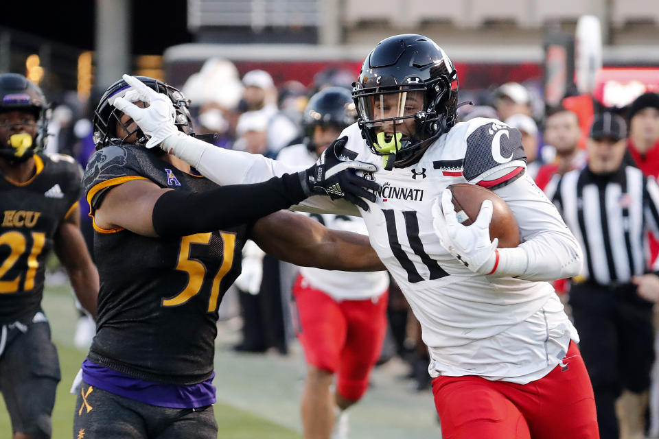 Cincinnati's Leonard Taylor (11) stiff-arms East Carolina's Aaron Ramseur (51) after catching the ball during the first half of an NCAA college football game in Raleigh, N.C., Friday, Nov. 26, 2021. (AP Photo/Karl B DeBlaker)