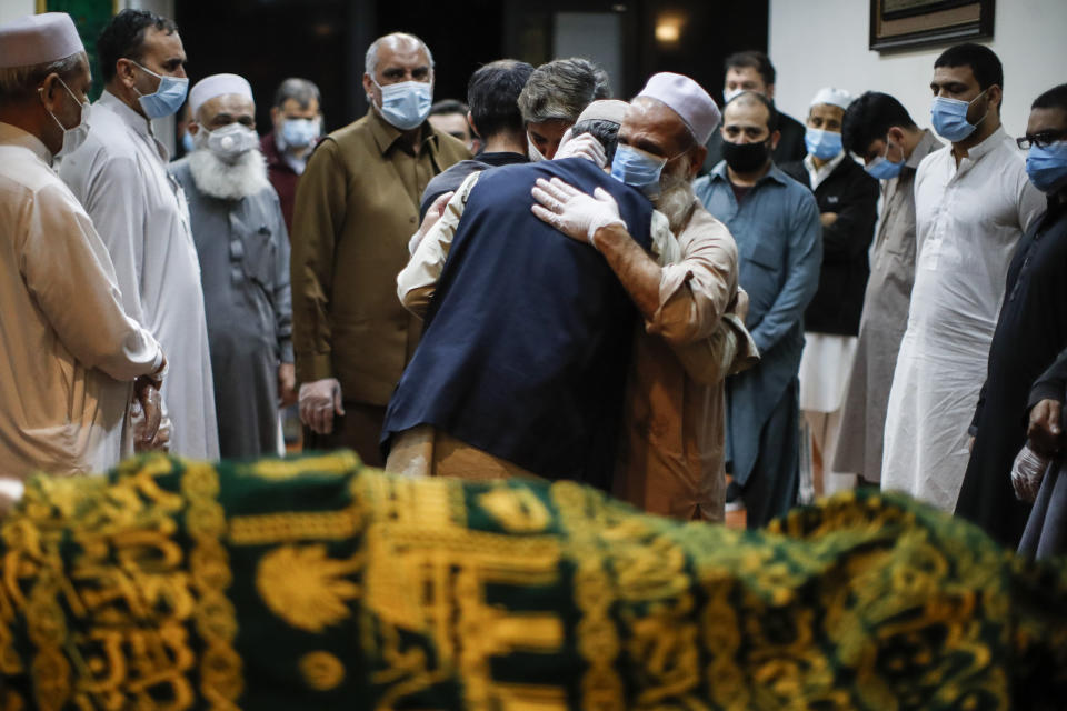 Mohammad Ayaz, cousin of Mohammad Altaf, center right, is hugged by a mourner after funeral prayers are given over Altaf's body at Al-Rayaan Muslim Funeral Services, Sunday, May 17, 2020, in the Brooklyn borough of New York. (AP Photo/John Minchillo)