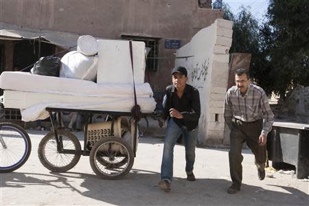 A Free Syrian Army fighter and a man run for cover fearing sniper fire at a Free Syrian Army checkpoint in Aleppo's Bustan al-Qasr, October 26, 2013. REUTERS/Mahmoud Hassano