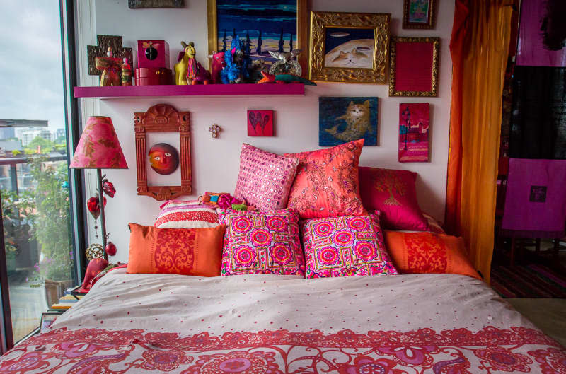 accessories fill the shelves in this eclectic pink and red bedroom