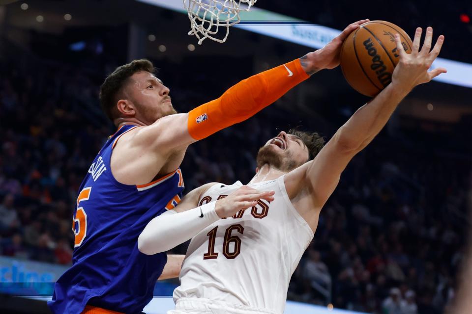 New York Knicks center Isaiah Hartenstein (55) blocks a shot by Cleveland Cavaliers forward Cedi Osman (16) during the first half of an NBA basketball game Friday, March 31, 2023, in Cleveland. (AP Photo/Ron Schwane)