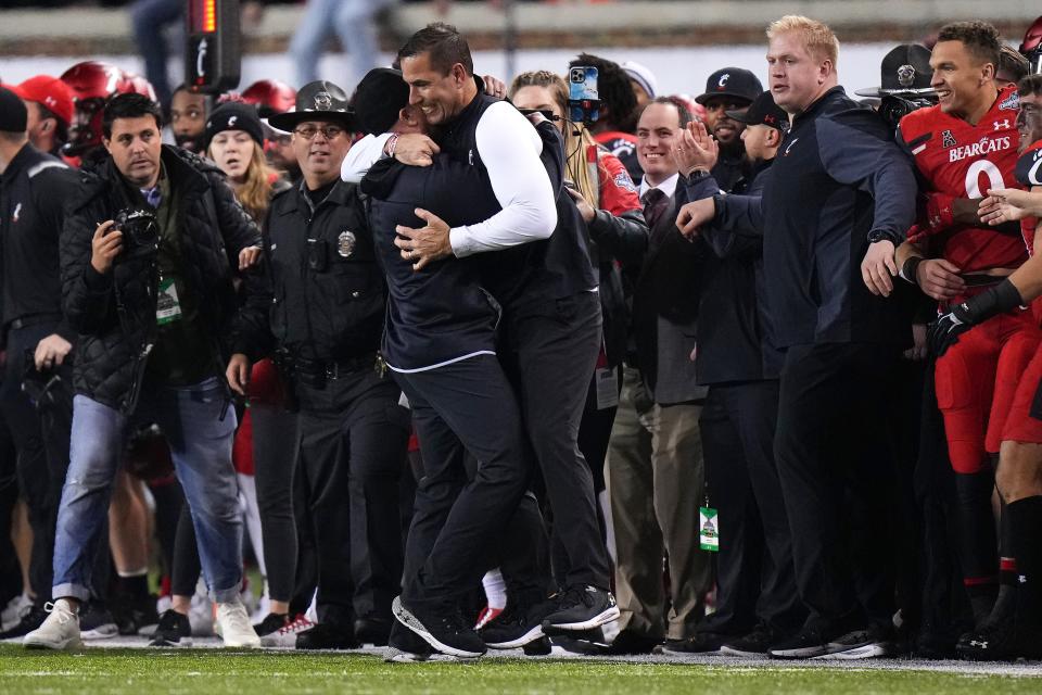 Cincinnati Bearcats head coach Luke Fickell embraces a coach on the sideline in the fourth quarter during the American Athletic Conference championship football game against the Houston Cougars, Saturday, Dec. 4, 2021, at Nippert Stadium in Cincinnati. The Cincinnati Bearcats won, 35-20. 