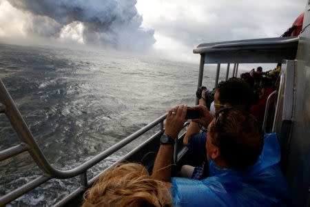 People watch from a tour boat as lava flows into the Pacific Ocean in the Kapoho area, east of Pahoa, during ongoing eruptions of the Kilauea Volcano in Hawaii, U.S., June 4, 2018. REUTERS/Terray Sylvester/Files