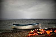 Life jackets and a boat that were used by refugees and migrants to cross the Aegean sea from Turkey lie abandoned on a beach on the Greek Island of Lesbos on October 8, 2015