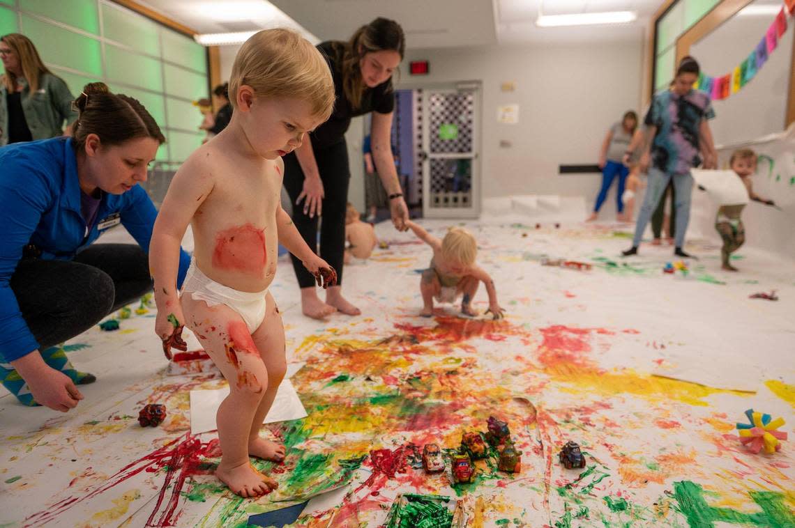Two-year-old Henry Sloderbeck covers his feet in paint during the baby paint crawl.
