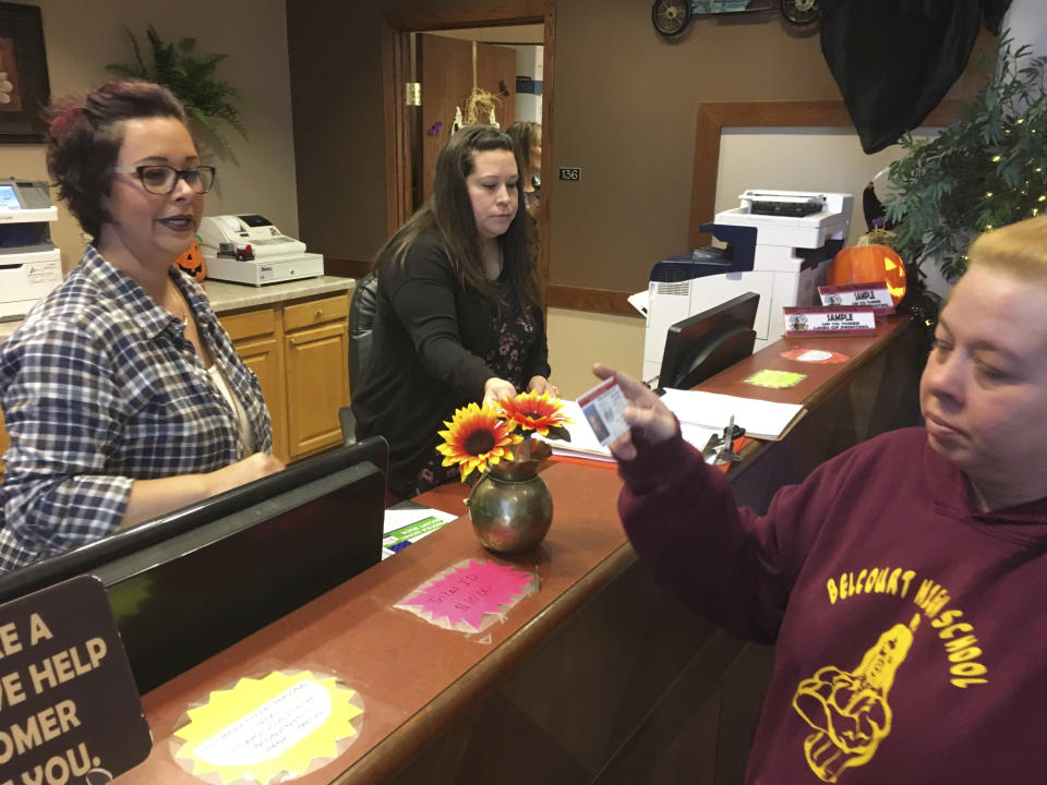 In this Oct. 24, 2018, photo, Delaine Belgarde, right, shows the new Turtle Mountain Band of Chippewa ID she received free of charge on Wednesday, in Belcourt, N.D. It will allow her to vote in November under recently tightened state voter ID rules. (AP Photo/Blake Nicholson)