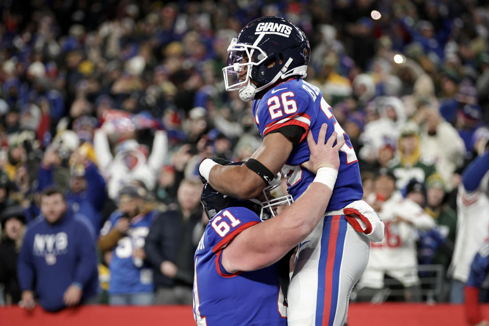 New York Giants running back Saquon Barkley (26) celebrates with center John Michael Schmitz Jr. (61) after scoring a touchdown against the Green Bay Packers during the second quarter of an NFL football game, Monday, Dec. 11, 2023, in East Rutherford, N.J. (AP Photo/Adam Hunger)
