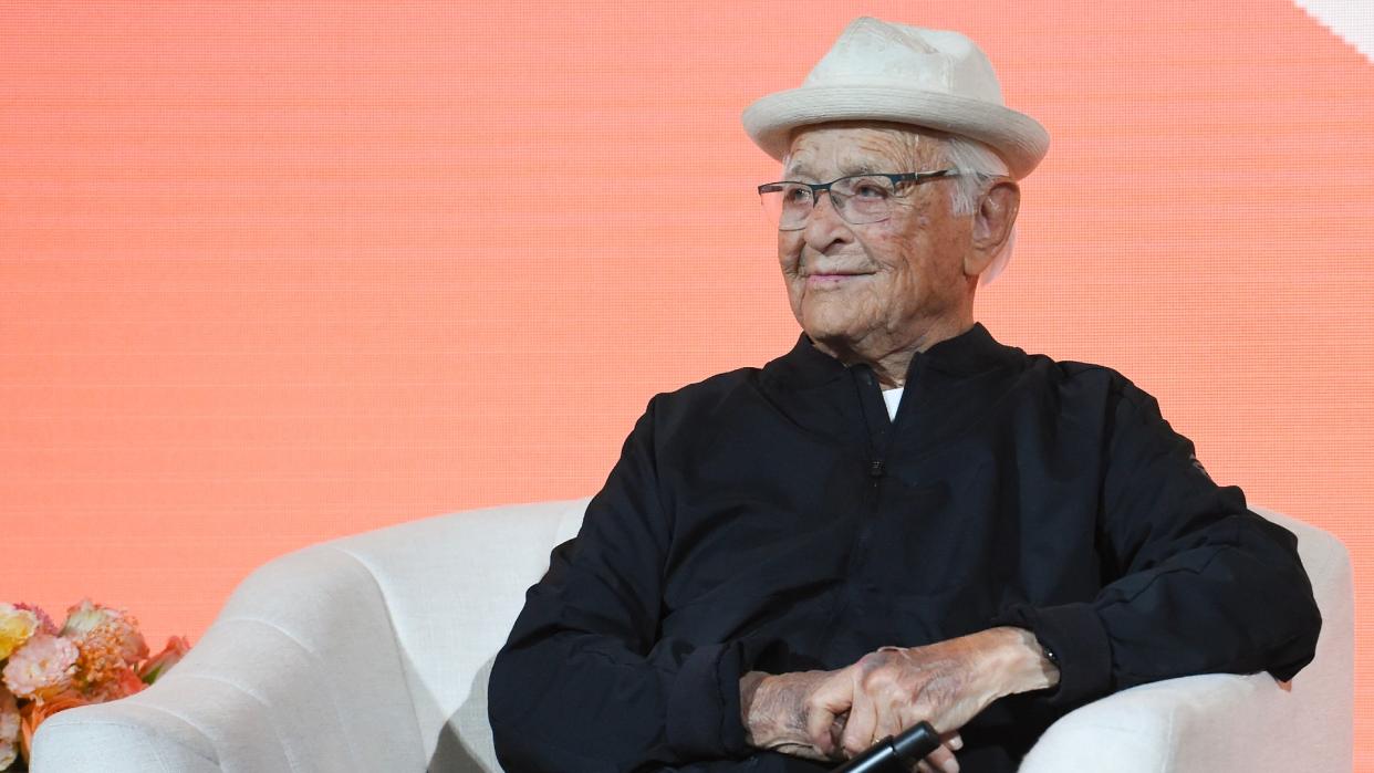  Norman Lear sitting in a white chair. 