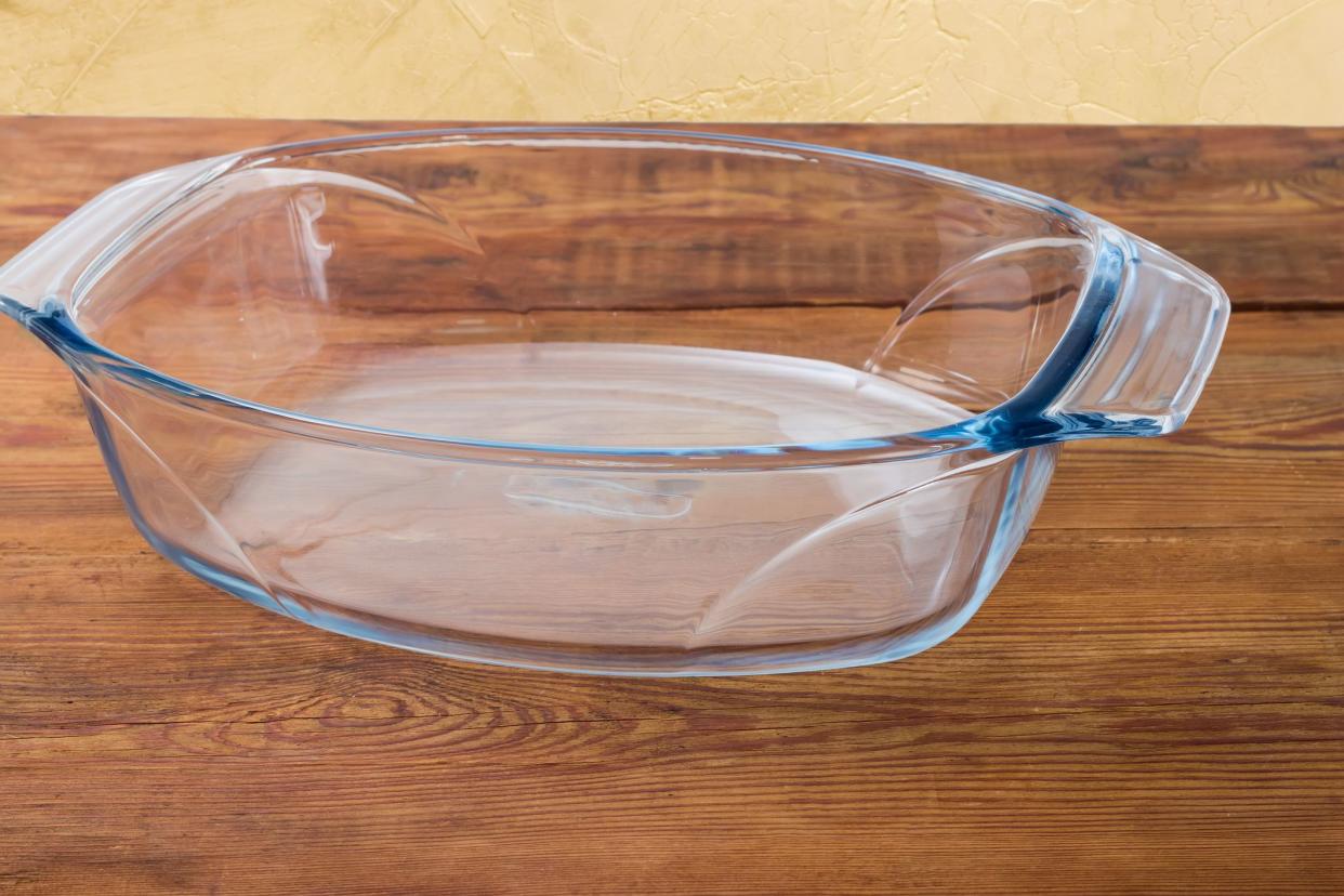 Empty oval glass casserole pan on an old rustic table close-up