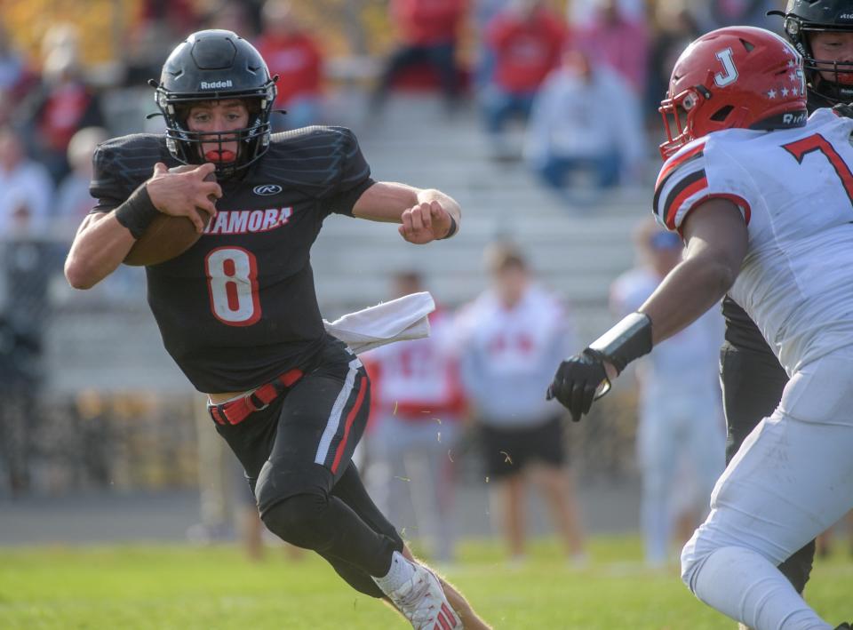 Metamora quarterback Kaden Hartnett scrambles to avoid Jacksonville's Deone Salther in the second half of their Class 5A first-round playoff game Saturday, Oct. 29, 2022 in Metamora. The Redbirds advanced with a 68-34 victory.